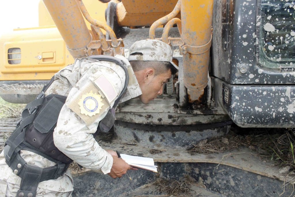 Un agente de la PNC identifica el código de la retroexcavadora decomisada en Punta de Manabique.